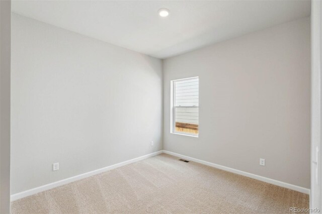 spare room featuring visible vents, baseboards, and light colored carpet