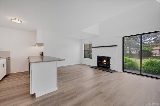 225 E 8th Ave Unit A2, Longmont, CO 80504 - unfurnished living room featuring light wood-style floors, a stone fireplace, and baseboards
