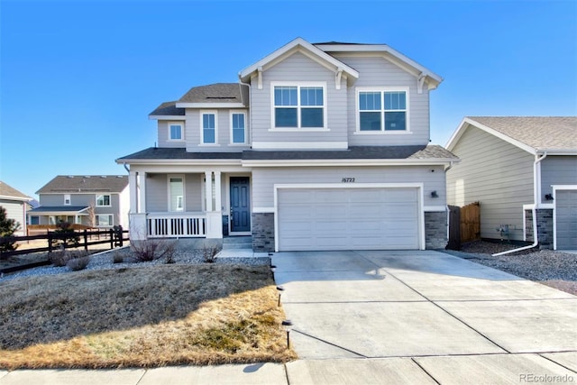 craftsman house featuring a porch, a garage, fence, driveway, and stone siding