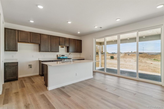 455 S Salida St, Aurora, CO 80017 - kitchen featuring light wood-style flooring, light countertops, dark brown cabinetry, recessed lighting, and a kitchen island with sink