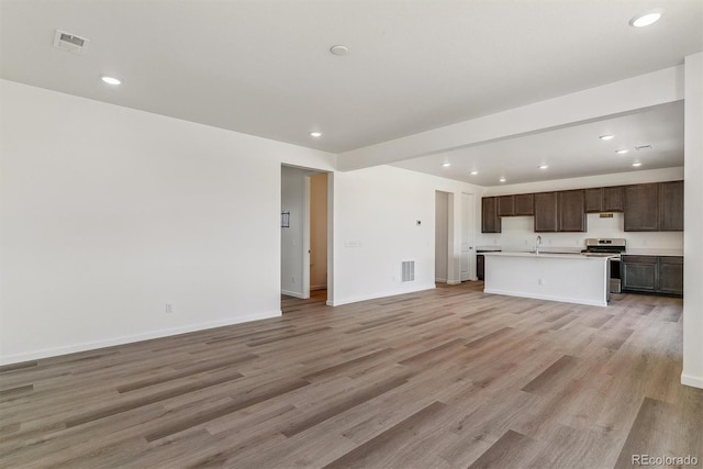 455 S Salida St, Aurora, CO 80017 - unfurnished living room with light wood-style floors, recessed lighting, baseboards, and a sink