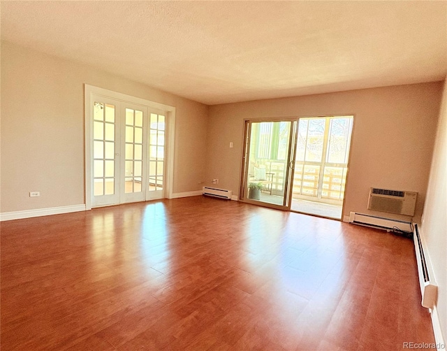 unfurnished room featuring a baseboard radiator, a wall mounted AC, wood finished floors, and baseboards