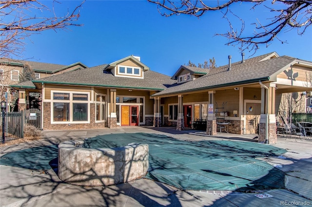 rear view of house with a covered pool, a patio area, and an outdoor kitchen