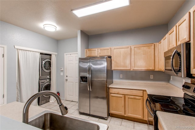 kitchen featuring stacked washing maching and dryer, light brown cabinets, stainless steel appliances, and sink