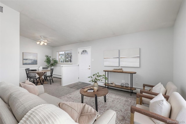 living room with light carpet, baseboard heating, and ceiling fan