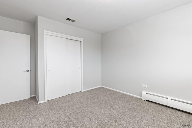 unfurnished bedroom featuring a closet, a baseboard heating unit, and carpet floors