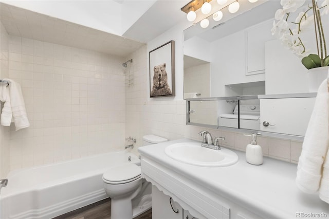 full bathroom featuring wood-type flooring, sink, tasteful backsplash, tiled shower / bath, and toilet