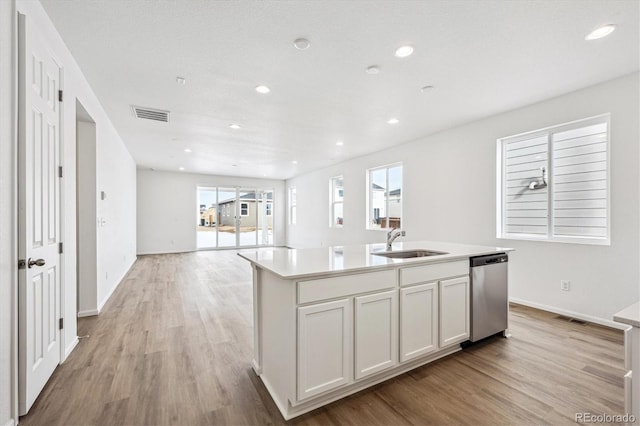 kitchen featuring light wood-type flooring, white cabinets, sink, a center island with sink, and dishwasher