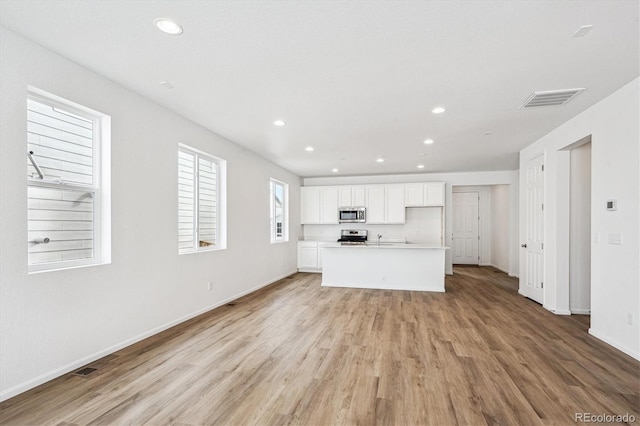 unfurnished living room featuring sink and light hardwood / wood-style floors