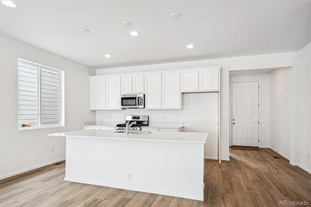 kitchen featuring white cabinets, stainless steel appliances, a center island with sink, and sink