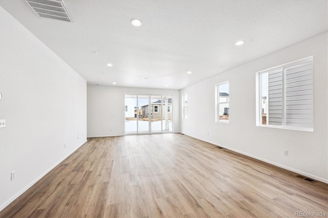 unfurnished living room with a textured ceiling and light hardwood / wood-style floors