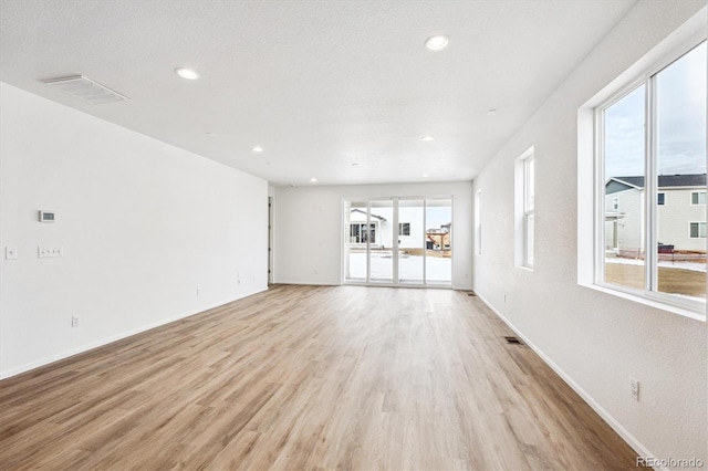 unfurnished living room featuring a textured ceiling and light wood-type flooring