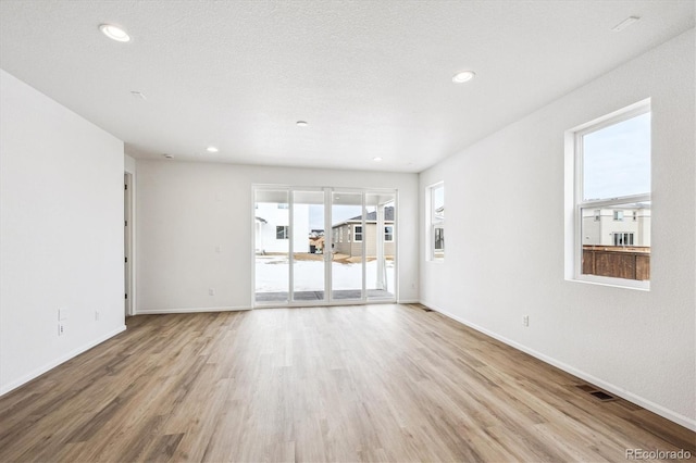 unfurnished room with light hardwood / wood-style floors and a textured ceiling