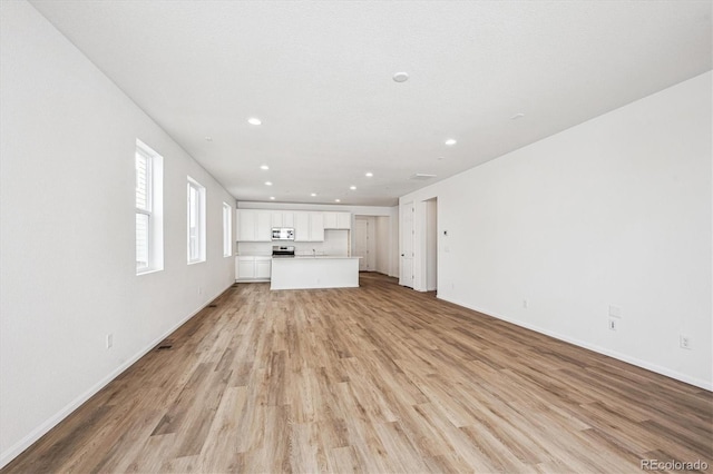 unfurnished living room featuring a textured ceiling and light hardwood / wood-style floors