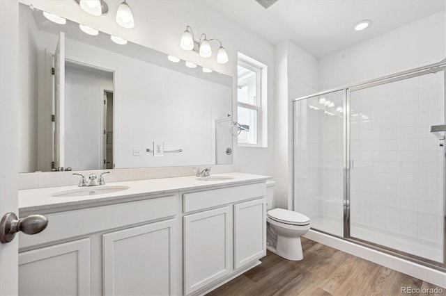 bathroom featuring wood-type flooring, vanity, toilet, and a shower with door