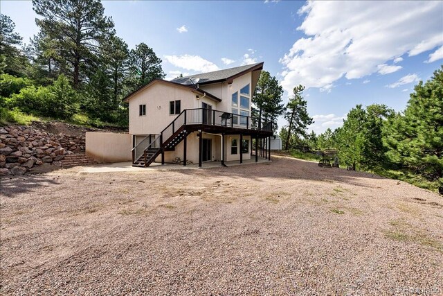 167 Wapiti Ct, Canon City, CO 81212 - back of property featuring stairway, a wooden deck, a patio, and dirt driveway