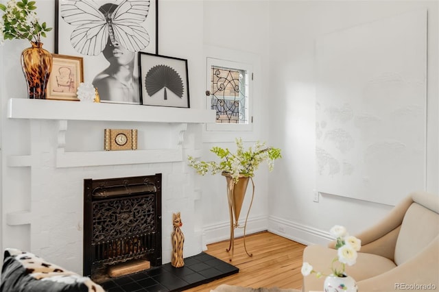 living room with baseboards, a tiled fireplace, and wood finished floors