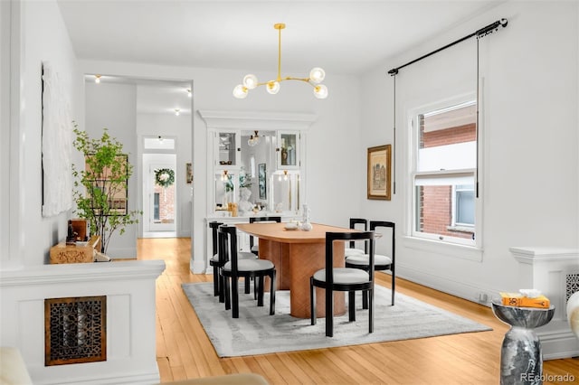 dining room featuring a notable chandelier, baseboards, and light wood-style floors