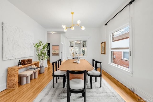 dining space with light wood finished floors, baseboards, and a chandelier