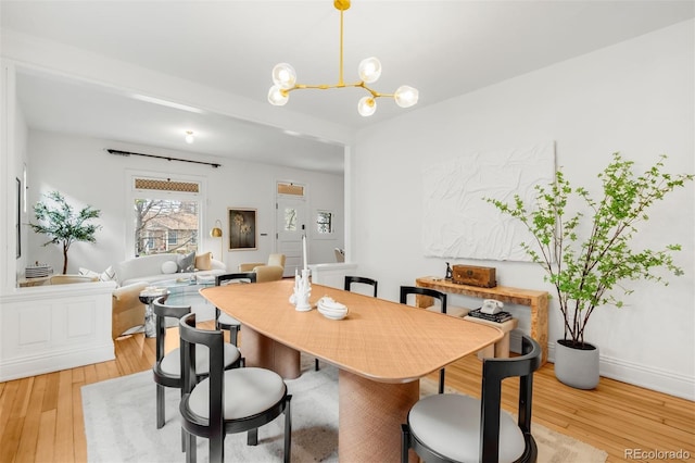 dining room featuring baseboards, a chandelier, and wood finished floors