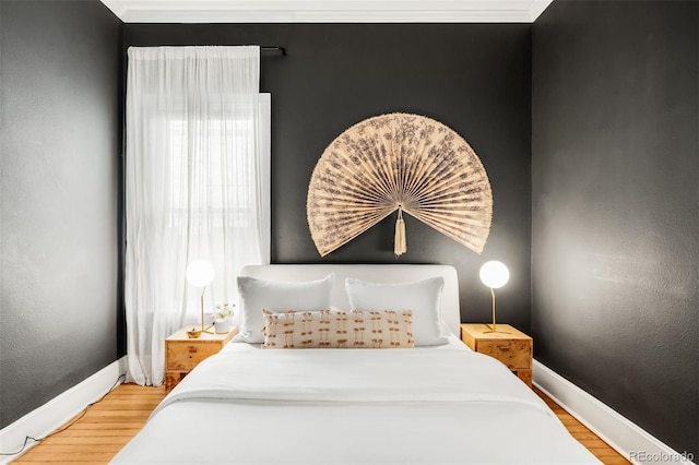 bedroom with a textured wall, baseboards, and wood finished floors