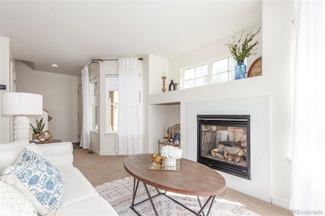 living room featuring a glass covered fireplace, carpet, and baseboards