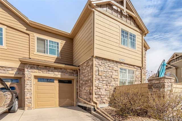 view of side of home with a garage, stone siding, and concrete driveway