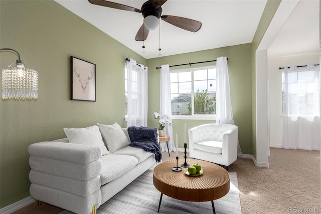 living area featuring baseboards, carpet floors, a ceiling fan, and plenty of natural light