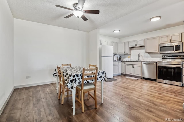 dining space featuring sink, hardwood / wood-style flooring, a textured ceiling, and ceiling fan