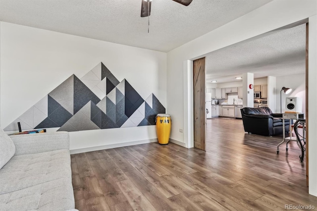 living room featuring ceiling fan, hardwood / wood-style flooring, and a textured ceiling