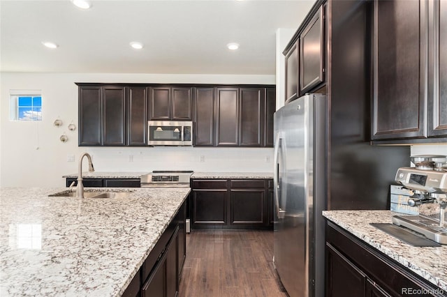 19316 W 84th Pl, Arvada, CO 80007 - kitchen featuring stainless steel appliances, a sink, dark wood-style flooring, dark brown cabinets, and light stone countertops