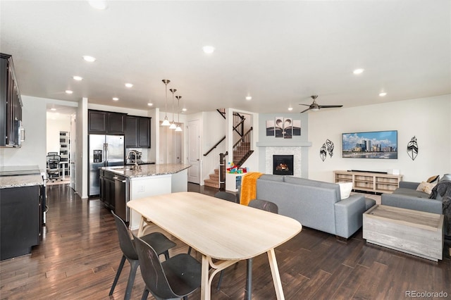 19316 W 84th Pl, Arvada, CO 80007 - dining area featuring stairs, a lit fireplace, ceiling fan, dark wood-style flooring, and recessed lighting