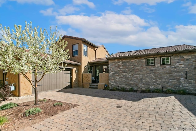 1819 La Bellezza Grv, Colorado Springs, CO 80919 - view of front of house with stone siding, a tiled roof, stucco siding, and decorative driveway