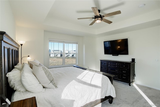 carpeted bedroom with a tray ceiling and ceiling fan