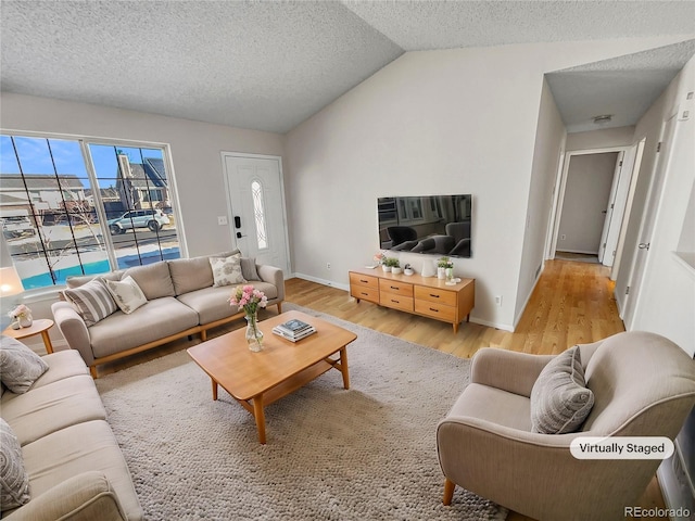 living room with a textured ceiling, light hardwood / wood-style flooring, and lofted ceiling