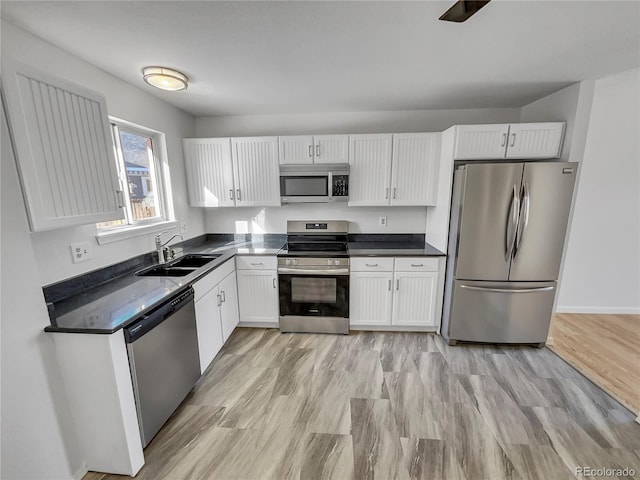 kitchen with light wood-type flooring, appliances with stainless steel finishes, sink, and white cabinetry