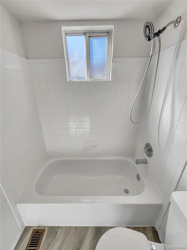 bathroom with toilet, tiled shower / bath combo, and wood-type flooring