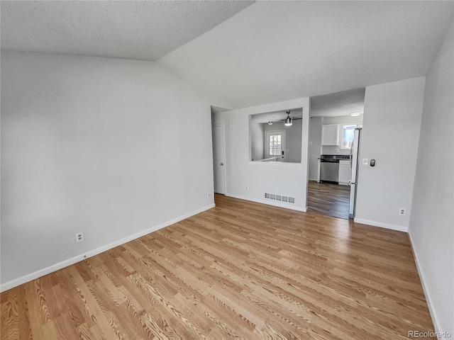 unfurnished living room featuring a textured ceiling, ceiling fan, lofted ceiling, and light hardwood / wood-style floors