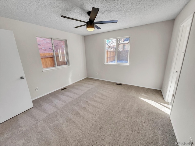 unfurnished bedroom with ceiling fan, light carpet, and a textured ceiling