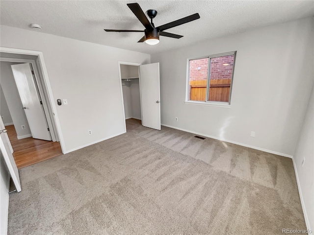 unfurnished bedroom featuring light carpet, ceiling fan, a textured ceiling, and a closet