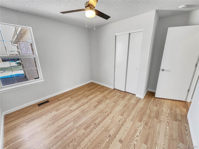 unfurnished bedroom featuring ceiling fan, a closet, a textured ceiling, and light hardwood / wood-style floors