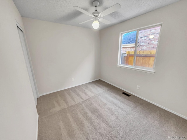 spare room featuring a textured ceiling, ceiling fan, and light colored carpet