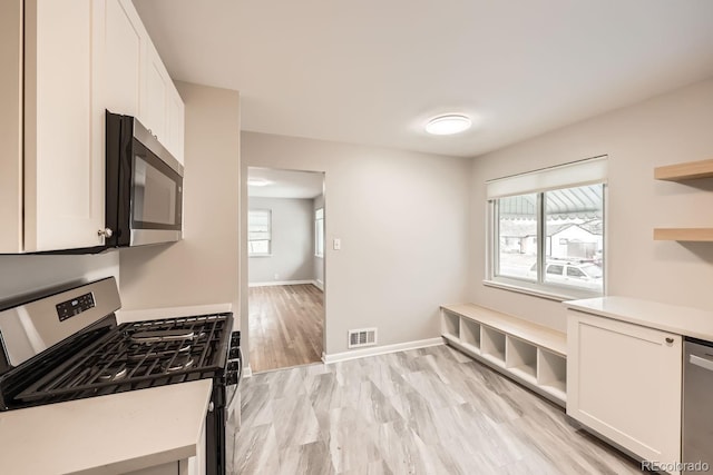 kitchen featuring visible vents, appliances with stainless steel finishes, white cabinetry, and open shelves