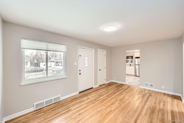 foyer entrance with visible vents, light wood-style flooring, and baseboards