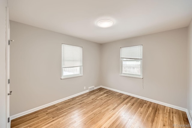 spare room featuring visible vents, light wood-type flooring, and baseboards