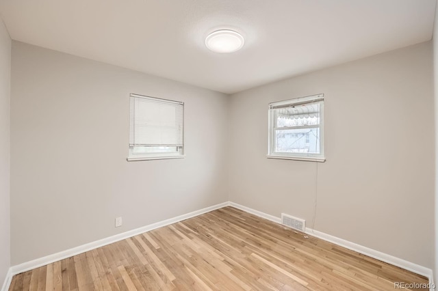 unfurnished room with light wood finished floors, visible vents, and baseboards