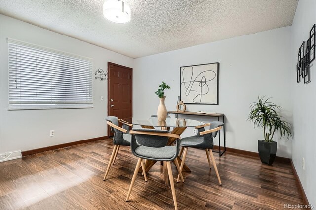 dining room featuring wood finished floors, baseboards, a textured ceiling, and visible vents