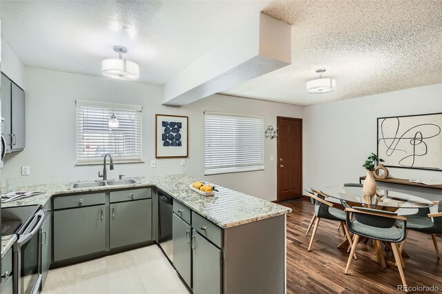 kitchen with a sink, a peninsula, a textured ceiling, and electric stove
