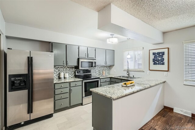 kitchen with a sink, gray cabinets, stainless steel appliances, a peninsula, and visible vents