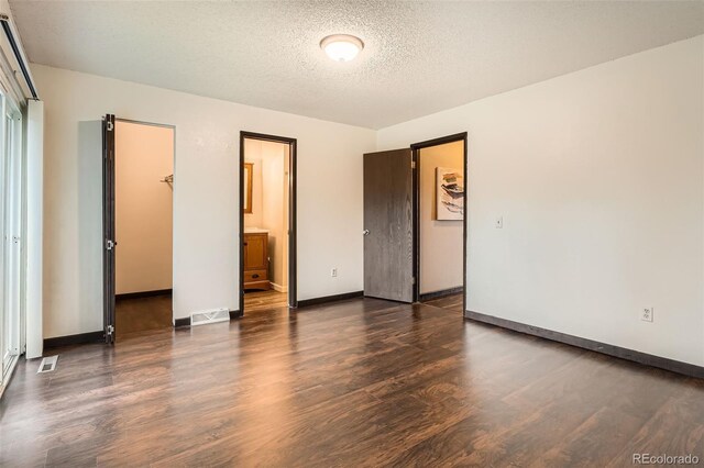 unfurnished bedroom with visible vents, a closet, wood finished floors, baseboards, and a spacious closet